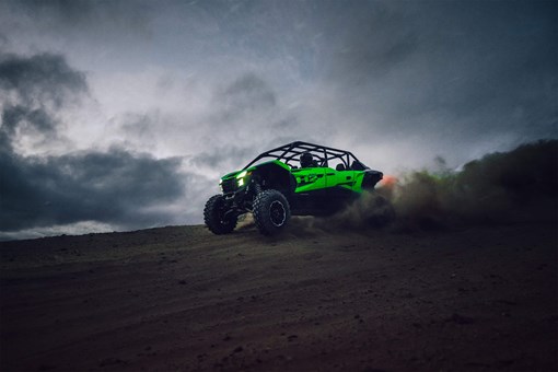 Three-quarter front angle of a person driving a side x side off-road. opens in a new window