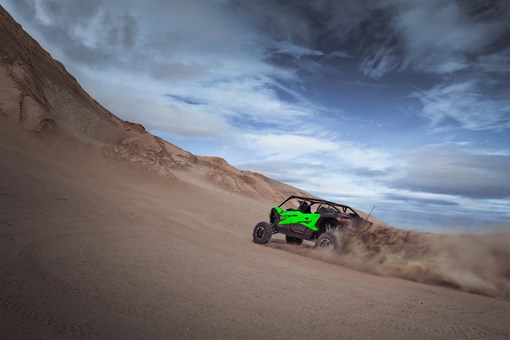 Rear angle of a person driving a side x side going up hill off-road. opens in a new window