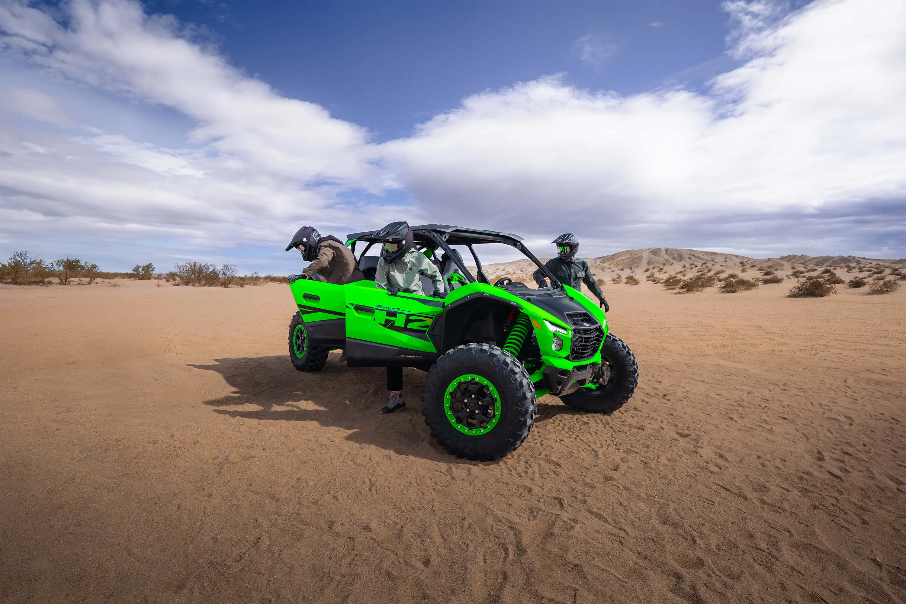 Three-quarter front angle of a side x side parked off-road with passengers getting out.