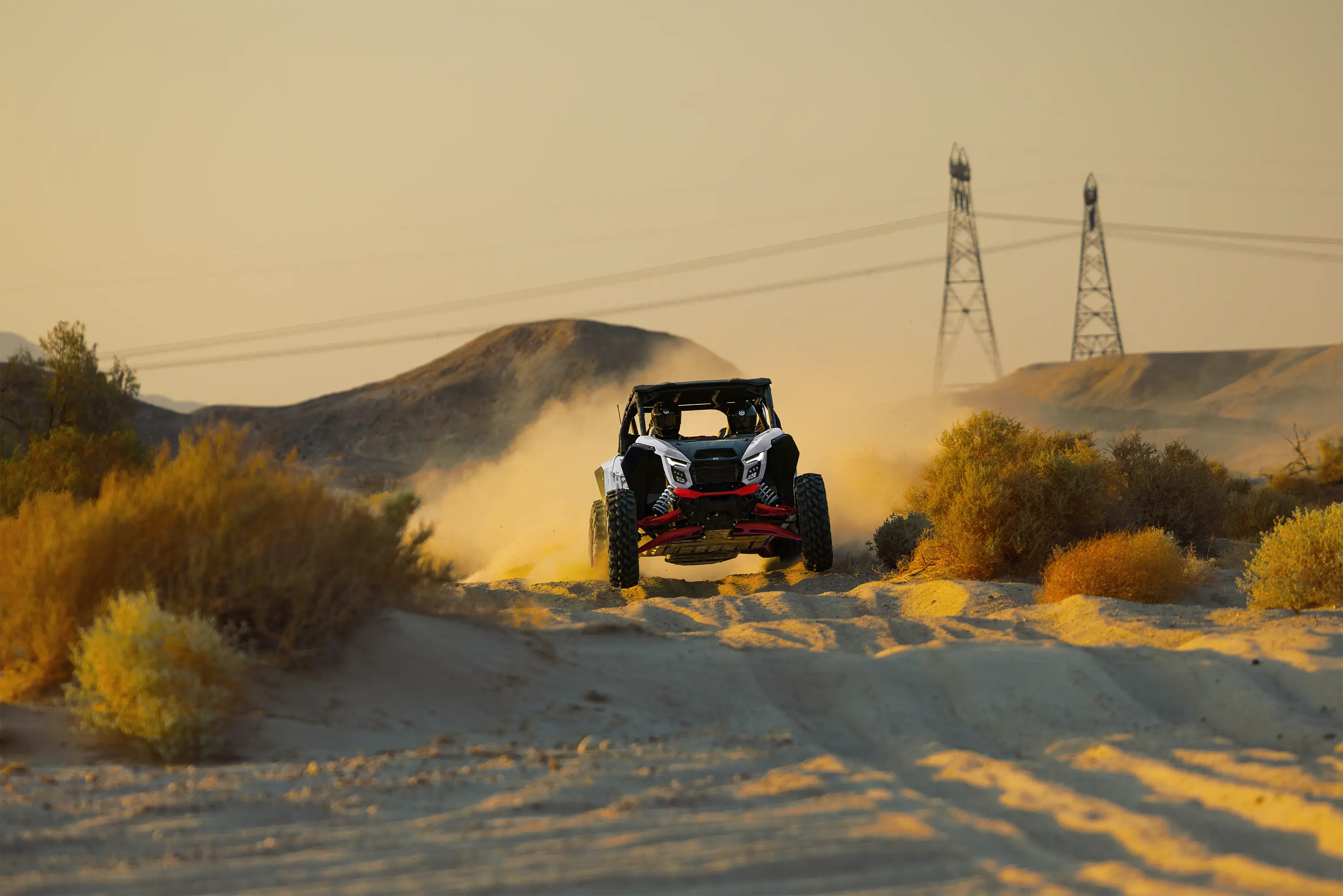 Front angle of a person driving a side x side on a desert road.