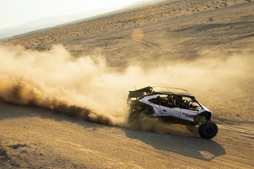 Side angle of a person driving a side x side in a desert. opens in a new window