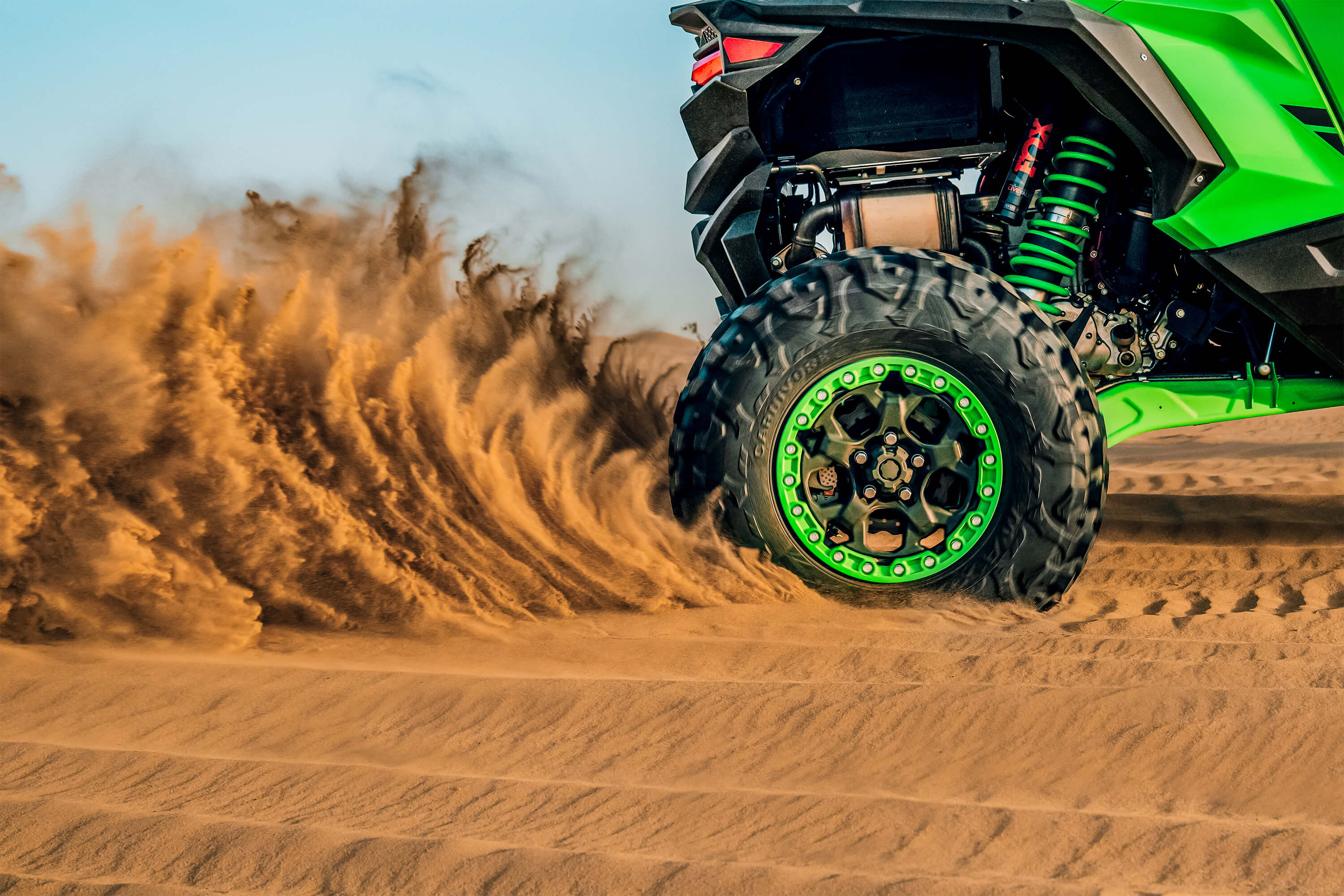 Close-up of a side x side wheel driving through sand off-road.