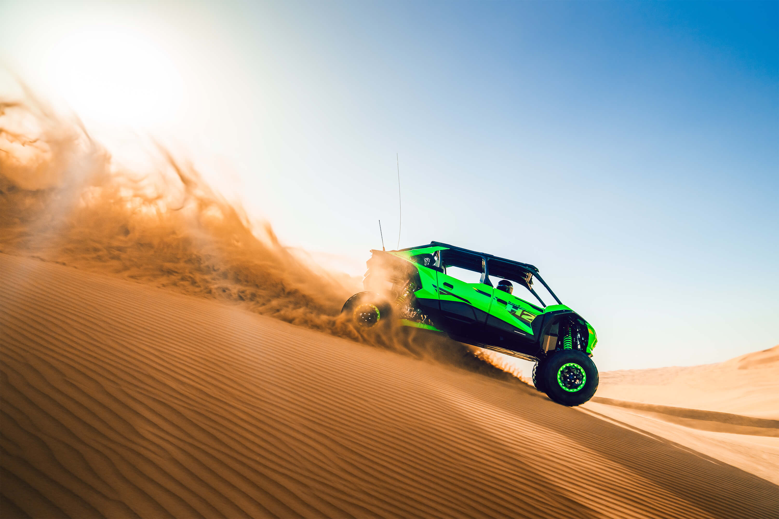 Side angle of a person driving a side x side down hill off-road.