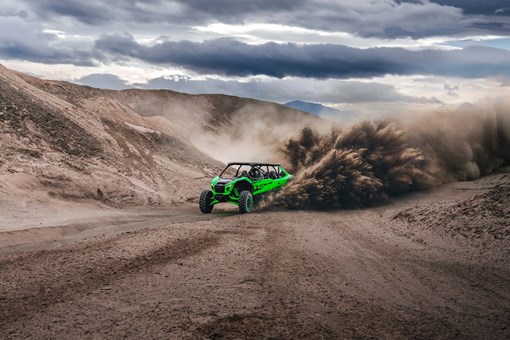 Front angle of a person driving a side x side off-road kicking up a big sand roost. opens in a new window