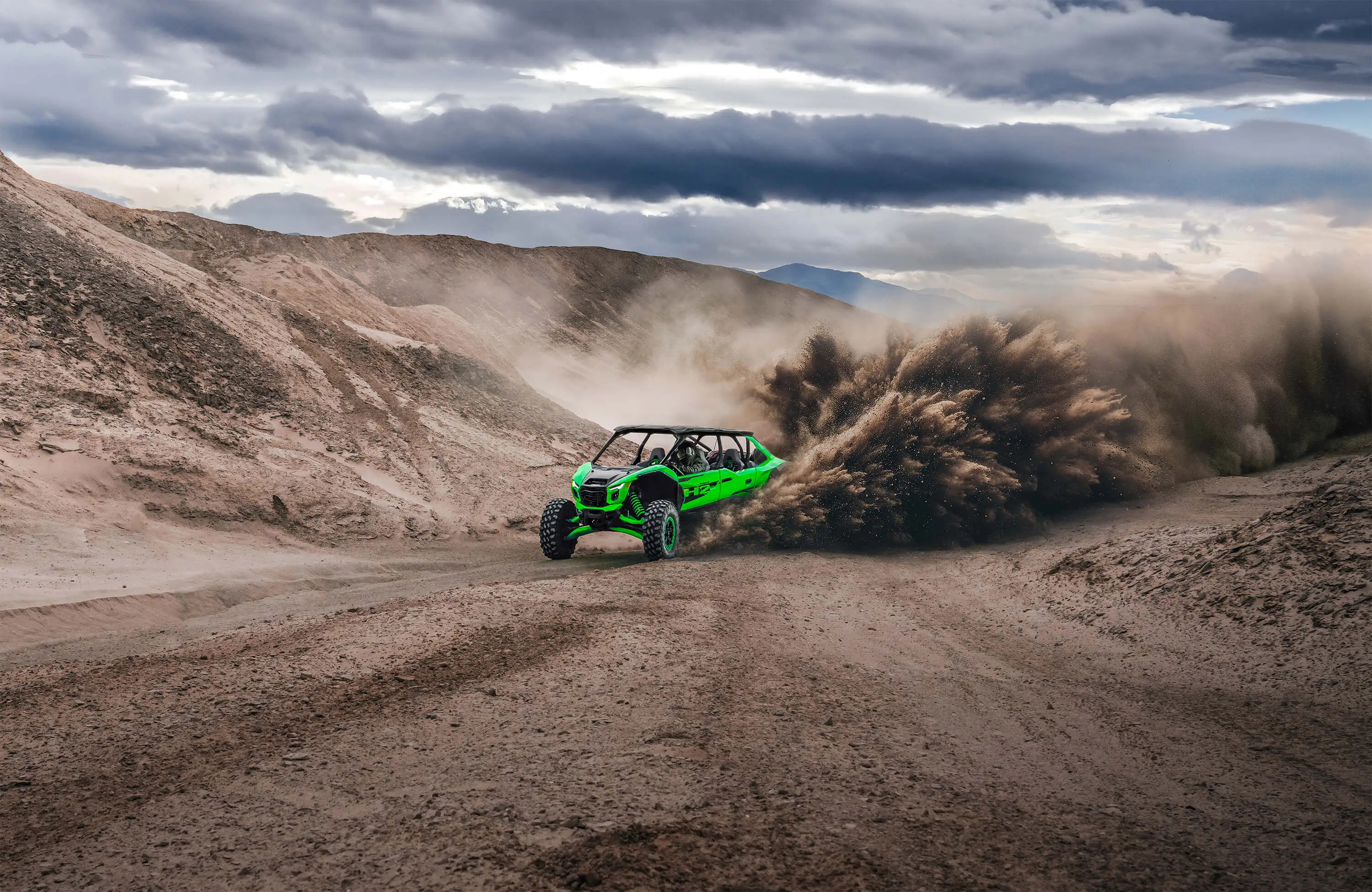 Front angle of a person driving a side x side off-road kicking up a big sand roost.