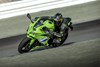 Three-quarter front angle of a person riding a motorcycle on a racetrack.