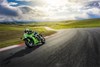 Three-quarter front angle of a person riding a motorcycle around a bend on a racetrack.