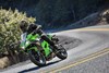 Three-quarter front angle of a person riding a motorcycle around a bend in a road.