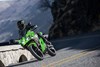 Three-quarter front angle of a person riding a motorcycle on a road.