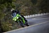 Front angle of a person riding a motorcycle around a bend in a road.