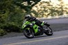 Side angle of a person riding a motorcycle on a road.