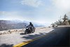 Three-quarter front angle of a person riding a black motorcycle on a road.