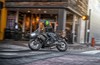 Profile angle of a person riding a black motorcycle on a city street.