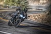 Three-quarter front angle of a person riding a black motorcycle on a curvy road.