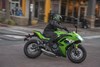 Side angle of a person riding a motorcycle on a city street.
