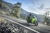 Three-quarter front angle of a person riding a motorcycle around a bend in the road.