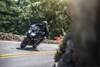 Front angle of a person riding a black motorcycle on a road.