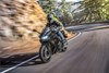 Three-quarter front angle of a person riding a black motorcycle around a bend in the road.