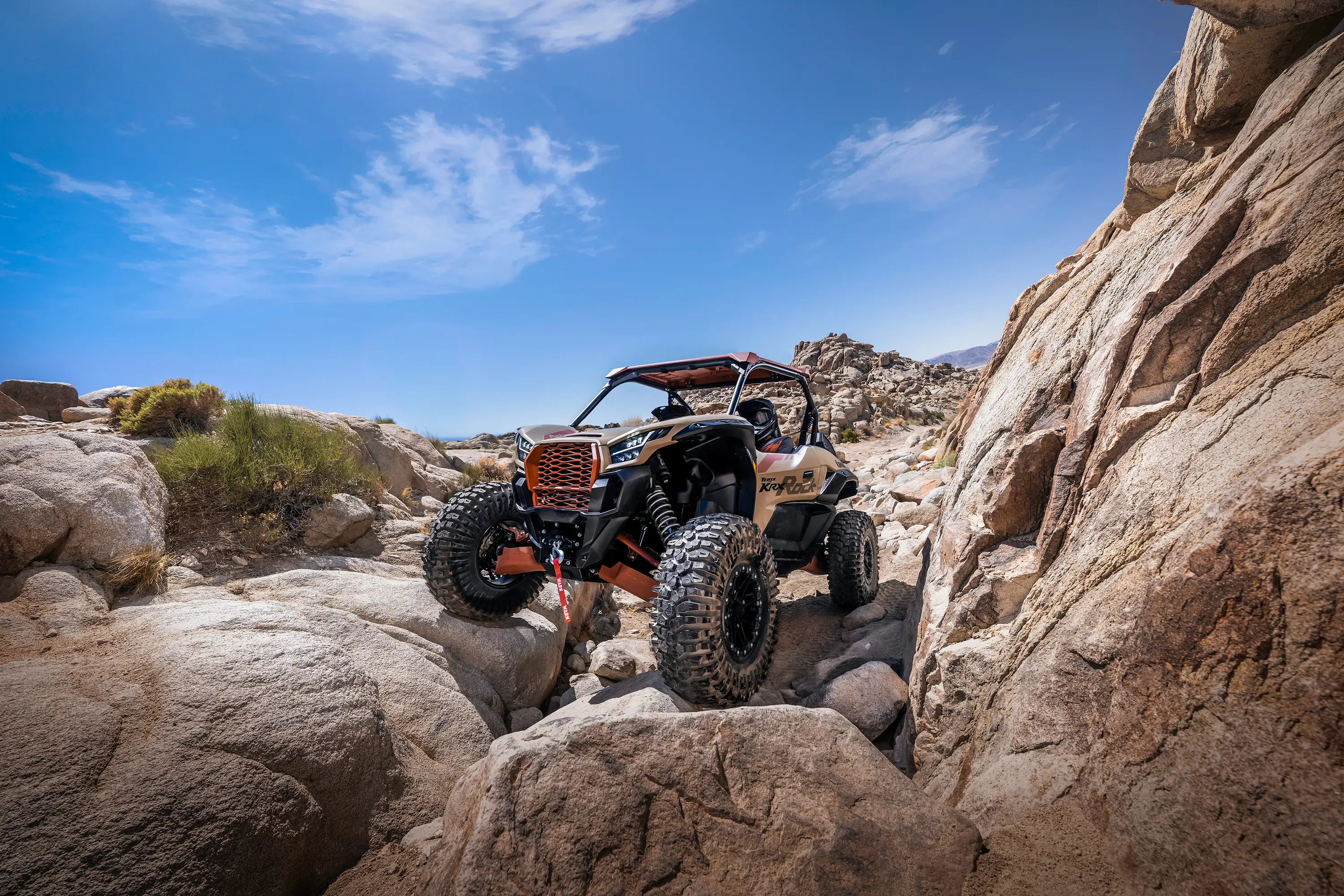 Three-quarter front angle of two people navigating a rock garden in a side x side.