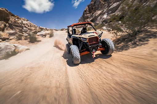 Front angle of two people riding a side x side off-road. opens in a new window