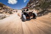 Front angle of two people riding a side x side off-road.
