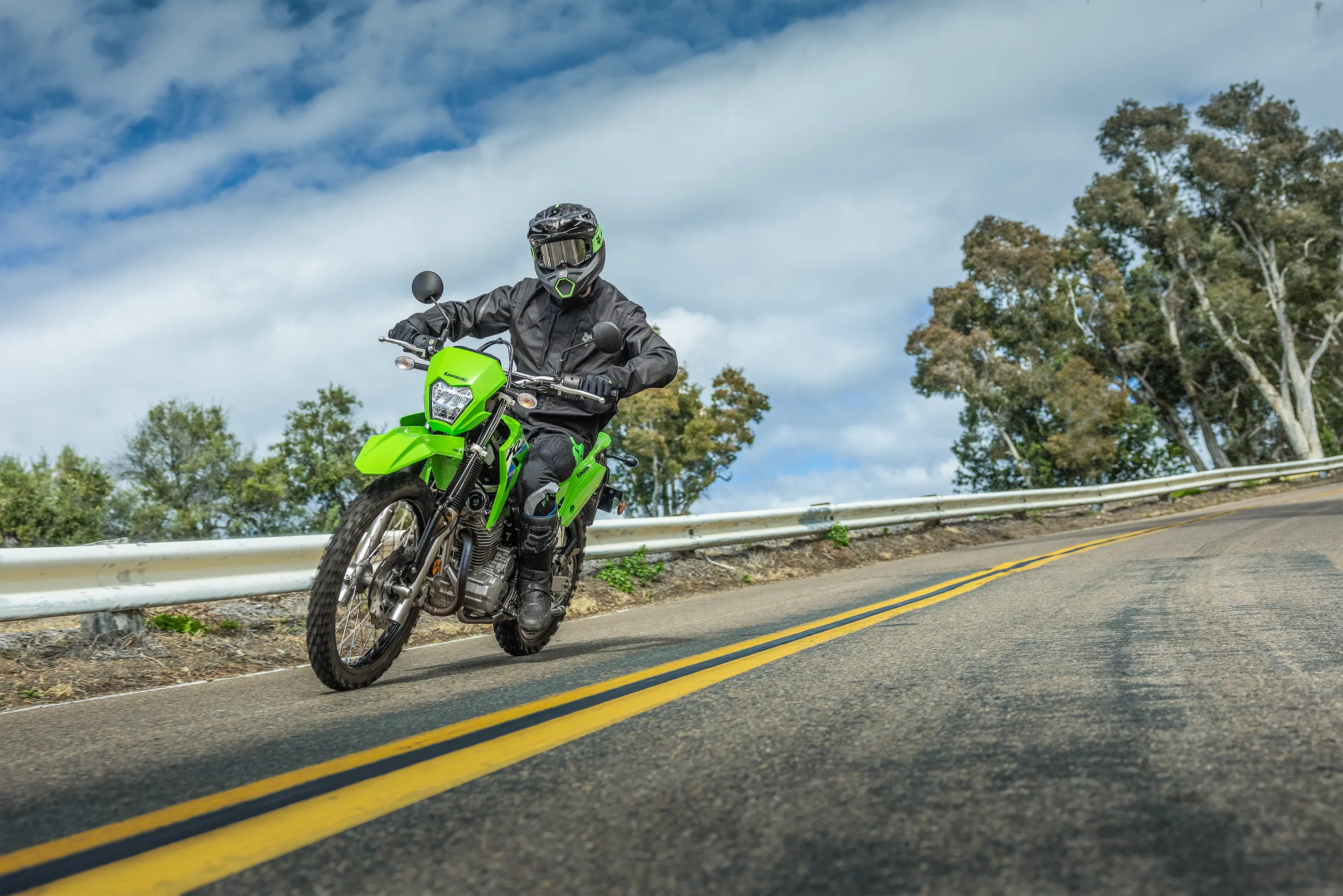 Three-quarter front angle of a person riding a motorcycle on a highway.