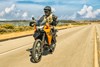 Three-quarter front angle of a person riding a motorcycle on a highway.