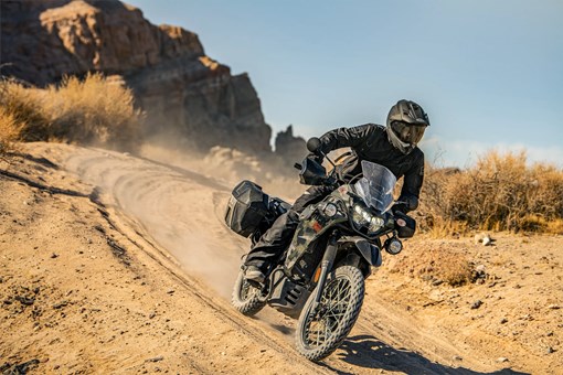 Three-quarter front angle of a person riding a motorcycle down a hill off-road. opens in a new window