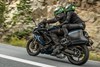 Side angle of two people riding a motorcycle on a highway.