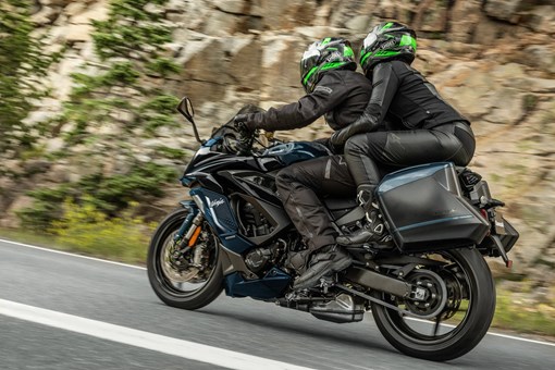 Side angle of two people riding a motorcycle on a highway. opens in a new window