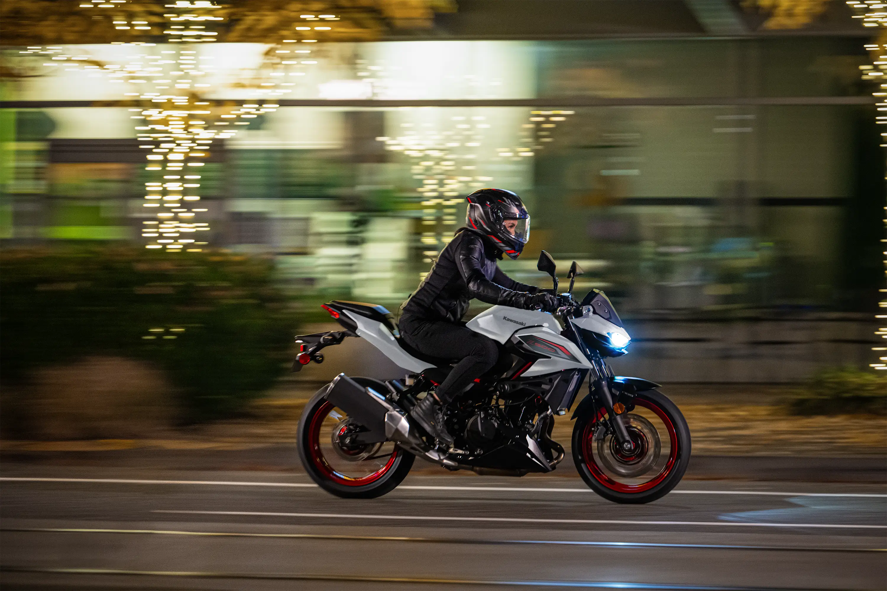 Side angle of a person riding a motorcycle on the street.