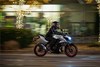 Side angle of a person riding a motorcycle on the street.
