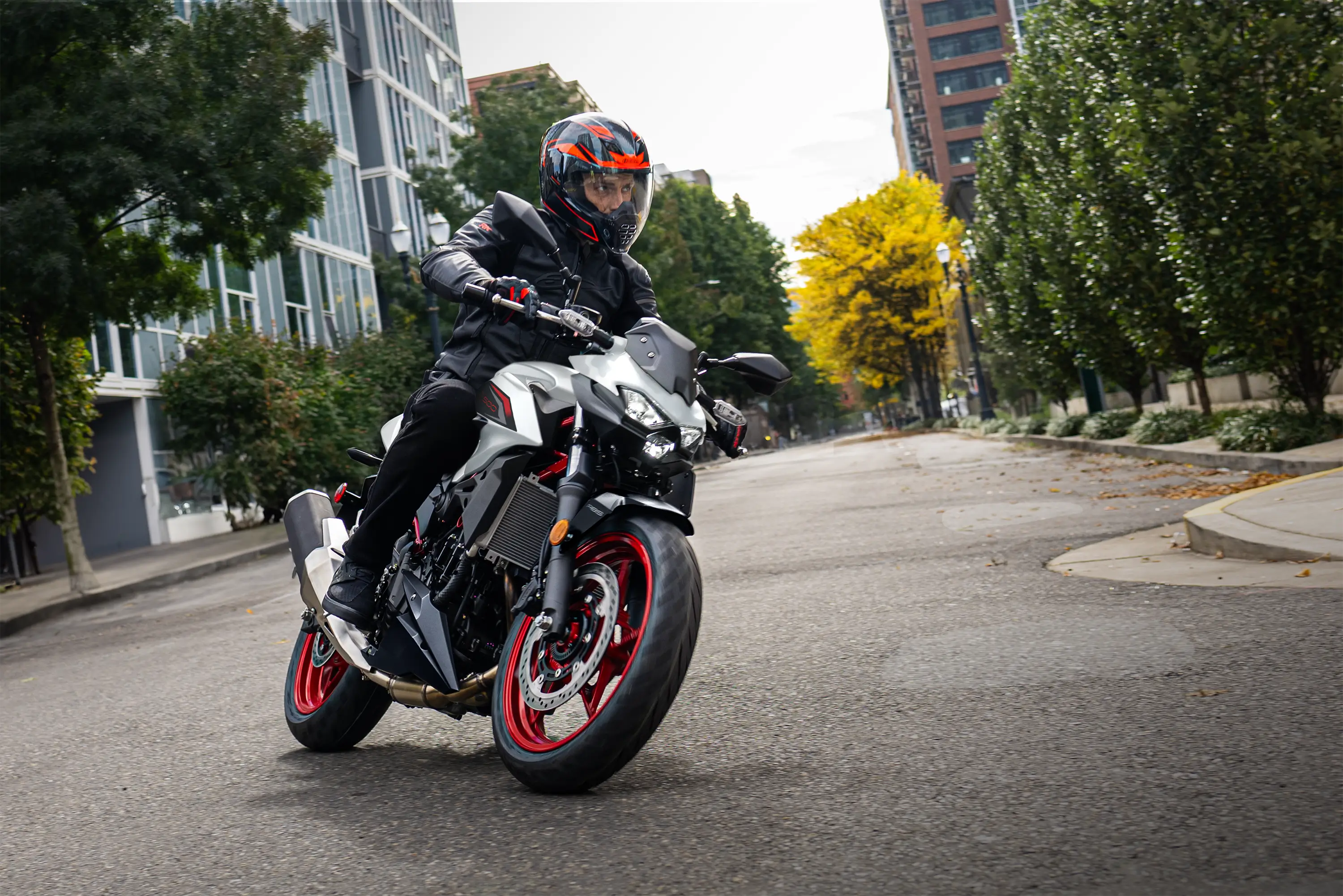 Three-quarter front angle of a person riding a motorcycle on the street.