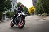 Three-quarter front angle of a person riding a motorcycle on the street.