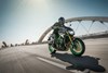 Three-quarter front angle of a person riding a motorcycle on a bridge.