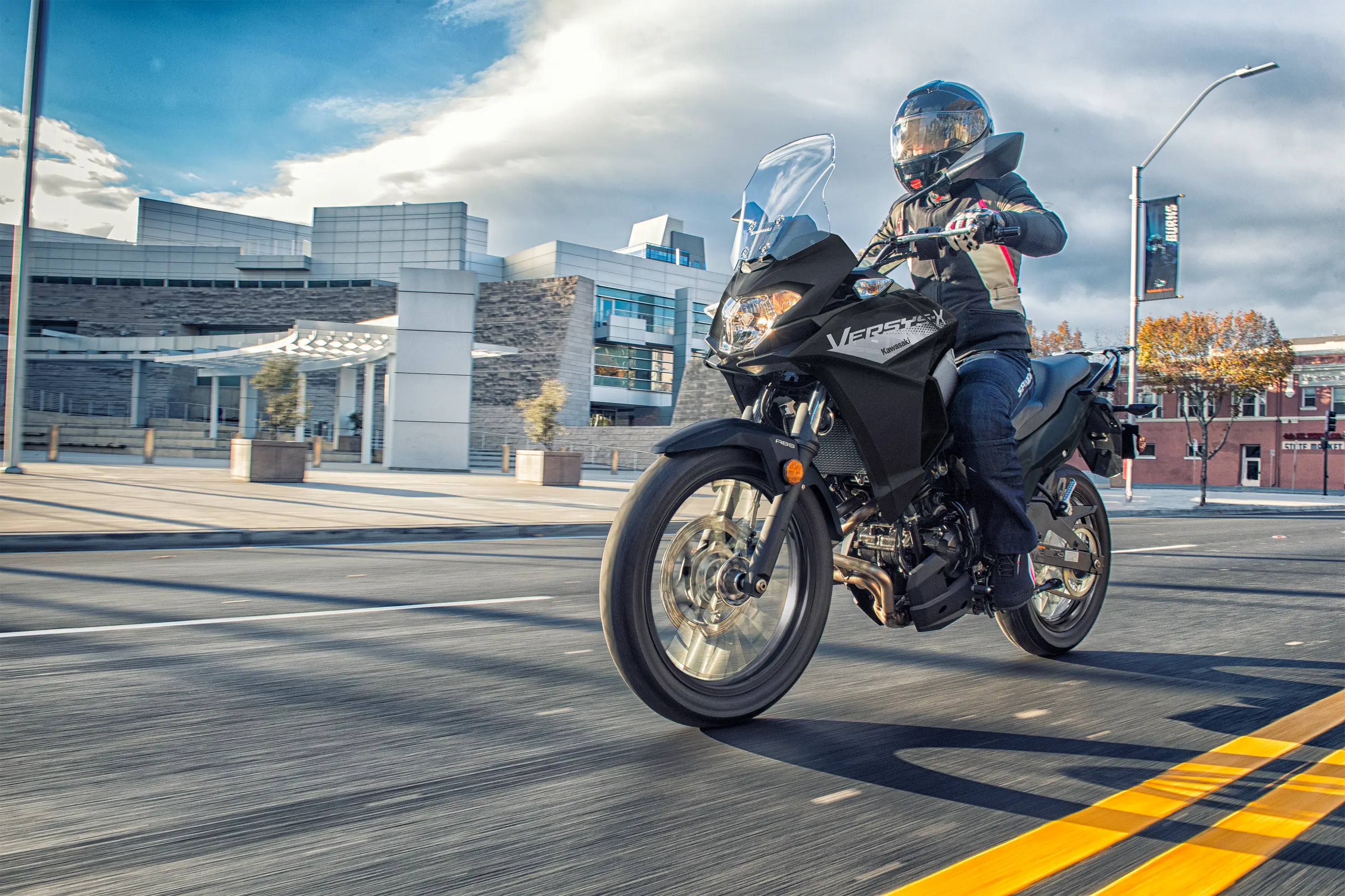 Three-quarter front angle of a person riding a motorcycle on the street.