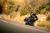 Three-quarter front angle of a person riding a motorcycle on a highway.
