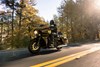 Front three-quarter angle of a person riding a motorcycle on a highway.