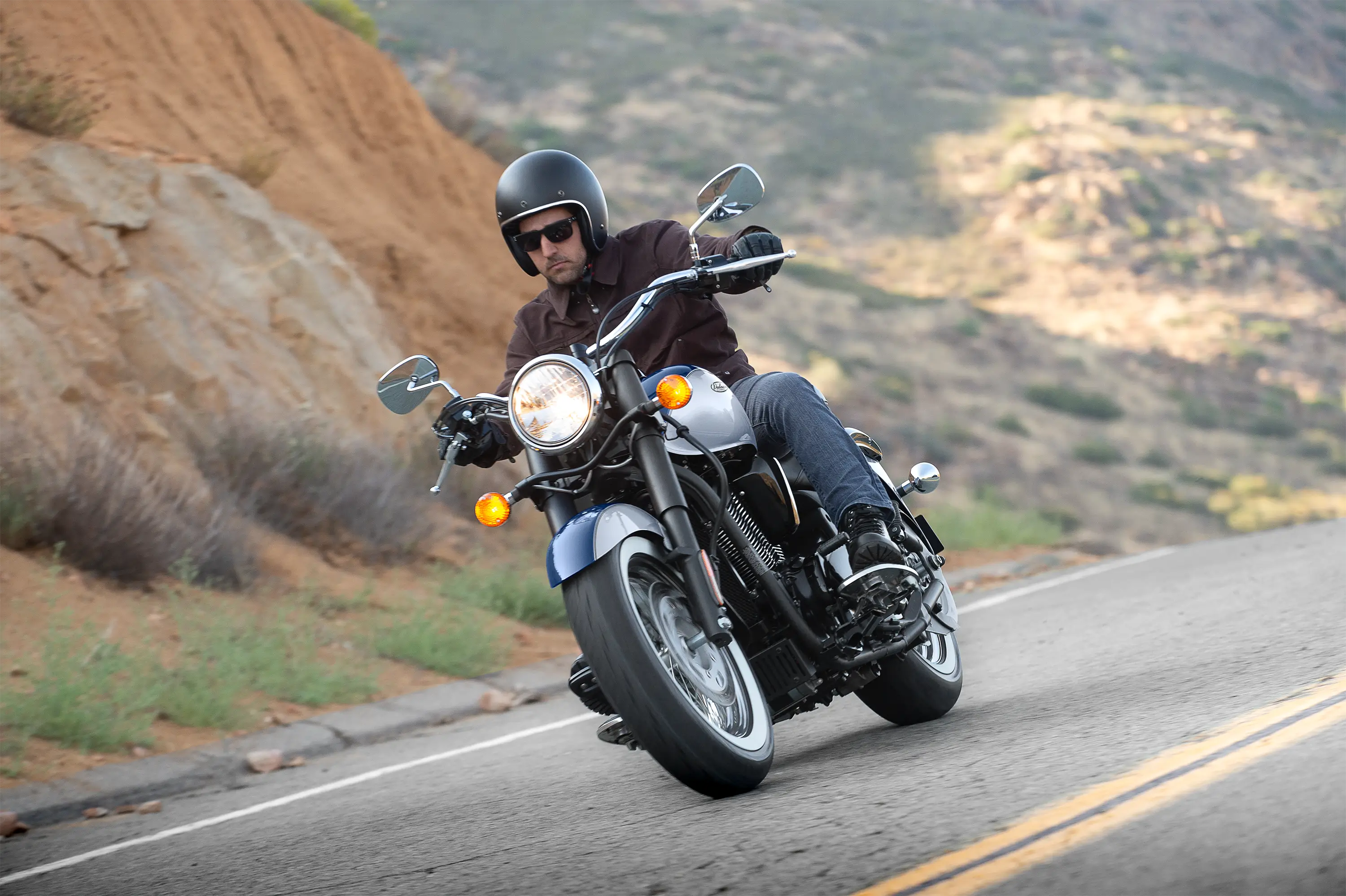 Three-quarter front angle of a person riding a motorcycle on a highway.