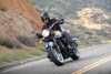 Three-quarter front angle of a person riding a motorcycle on a highway.