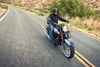 Front three-quarter angle from above of a person riding a motorcycle on a highway.