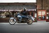 Side angle of a person riding a motorcycle on the street.