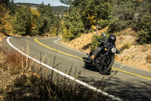 Three-quarter front angle of a person riding a motorcycle on a highway. opens in a new window