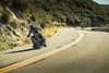 Front three-quarter angle of a person riding a motorcycle on a curvy highway.