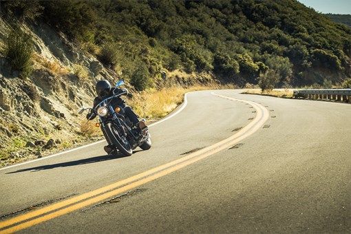 Front three-quarter angle of a person riding a motorcycle on a curvy highway. opens in a new window