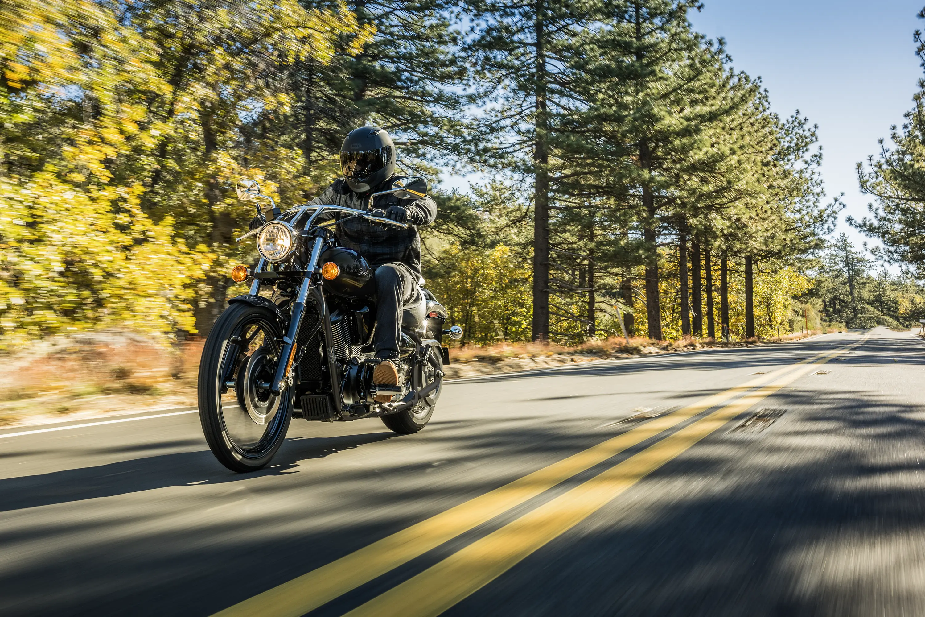 Front three-quarter angle of a person riding a motorcycle on a highway.