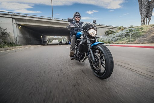 Three-quarter front angle of a person riding a motorcycle on the street. opens in a new window