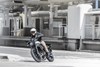 Front three-quarter angle of a person riding a motorcycle on the street.