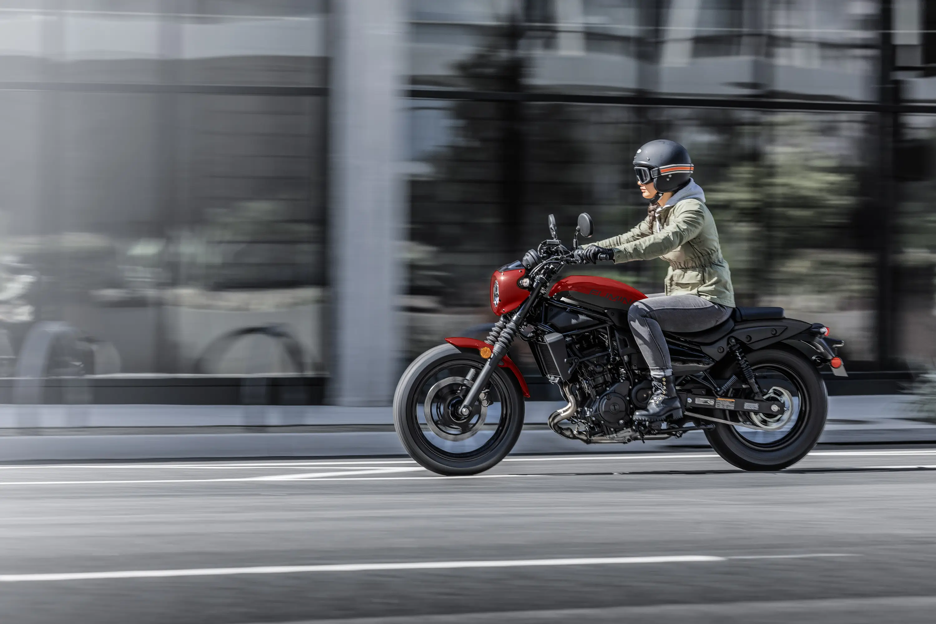 Side angle of a person riding a motorcycle on the street.