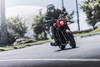Three-quarter front angle of a person riding a motorcycle on the street.